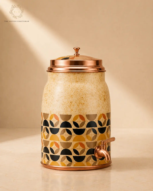 A ceramic beverage dispenser with a copper lid and spout, featuring a cream speckled upper body and a geometric pattern band in mustard yellow, black, and taupe around the lower half, set against a warm beige background.