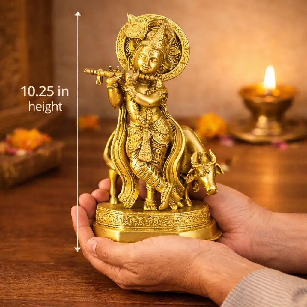 Gold-colored statue of a deity held by a person with a candle in the background