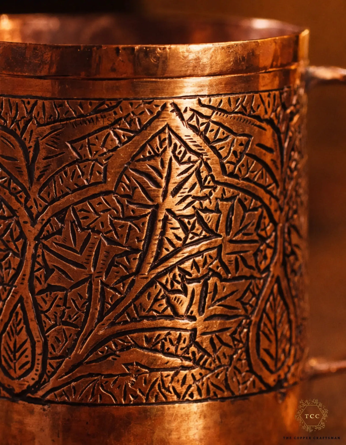 Copper cup with intricate leaf patterns on a warm brown background
