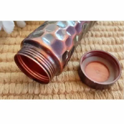 Copper-colored bottle with a textured surface on a woven mat background
