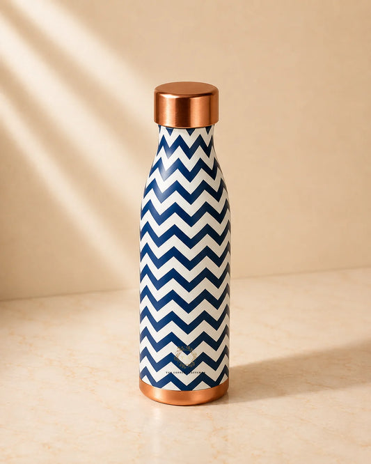 A Copper Water Bottle 1000ml (PRINTED)with a navy blue and white chevron pattern and metallic copper-colored lid and base, standing on a beige surface with soft diagonal shadows.