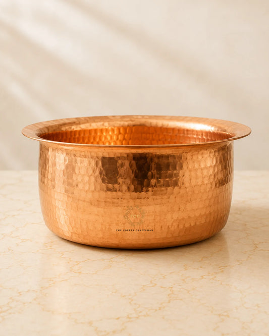 A hammered copper bowl 4.2 L with a flared rim, sitting on a light beige marble surface against a soft beige fabric backdrop.