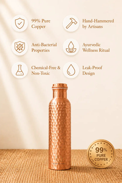 A hammered copper water bottle stands on a woven beige surface against a warm cream background. Text callouts around the bottle highlight features such as 99% pure copper, hand-hammering by artisans, anti-bacterial properties, ayurvedic wellness ritual, chemical-free and non-toxic design, and leak-proof construction.