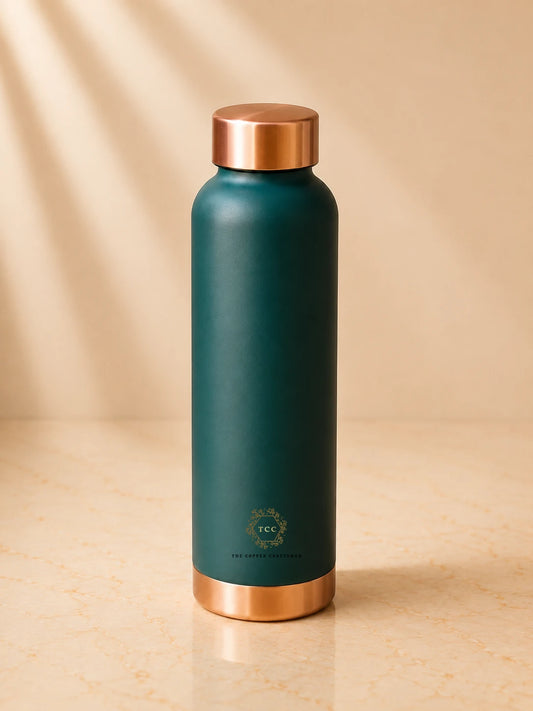A green colour copper water bottle with metallic rose gold accents on the lid and base, standing on a beige marble surface with soft diagonal shadows.