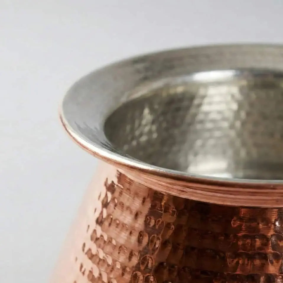 Copper and stainless steel cup with textured design on a white background