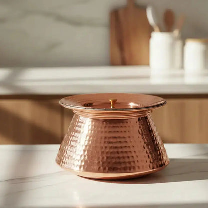 Copper pot on a marble surface with a blurred kitchen background