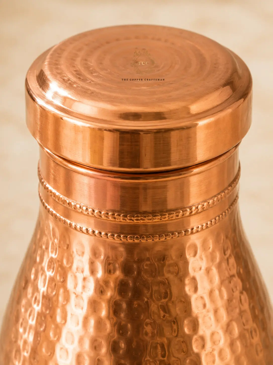 Close-up of a hammered Copper Bedroom Jar 1L with a matching copper screw-top lid, shown against a warm beige background.
