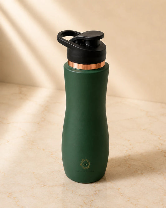 A matte dark green insulated copper bottle  with a black flip-top lid and a metallic copper collar, standing on a beige marble surface with soft diagonal shadows.