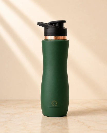 A dark green insulated copper bottle with a black flip-top lid and a metallic rose gold collar, standing on a light beige marble surface with soft diagonal shadows.