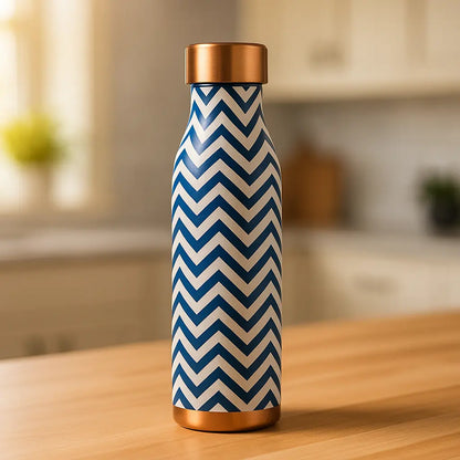 Blue and white chevron-patterned water bottle with a copper cap on a wooden surface.