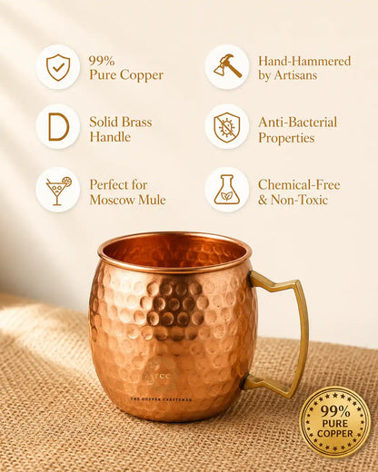 A hammered copper Moscow Mule mug with a brass handle, displayed on a burlap surface with promotional text icons and a badge highlighting pure copper and artisan hand-hammering.